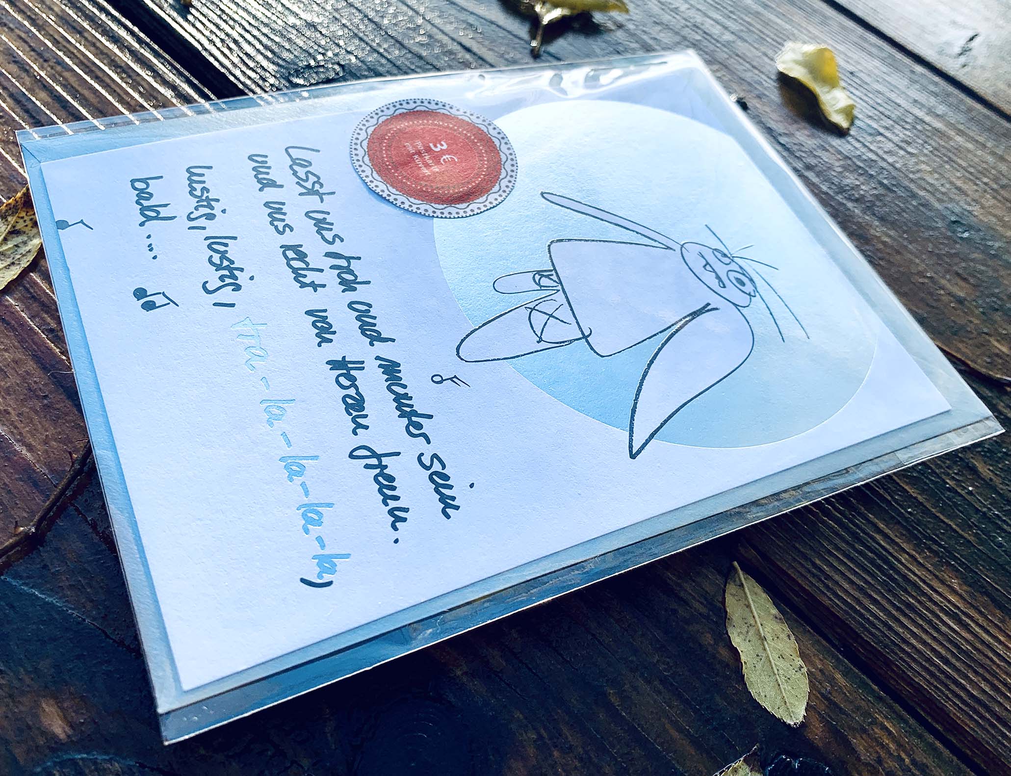 Weihnachtskarte „tra - la - la - la - la, bald… müder Engel“ mit silbernem Kuvert – stilvolle und humorvolle Postkarte für Weihnachten und Engel-Liebhaber. Seitenansicht mit Klarsichthülle und  Glanz