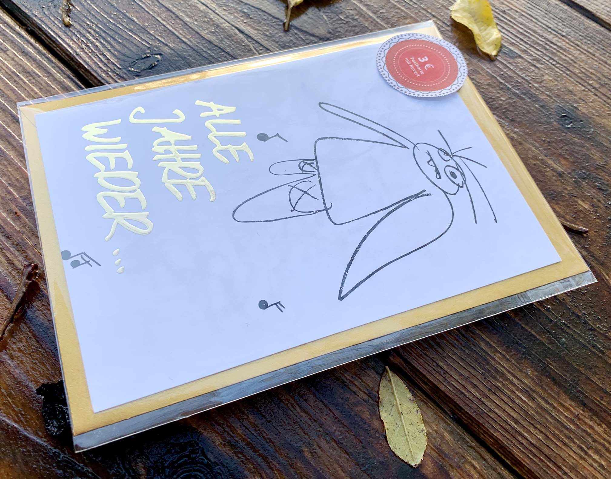 Weihnachtskarte „ ALLE JAHRE WIEDER… müder Engel“ mit goldenem Kuvert – stilvolle und humorvolle Postkarte für Weihnachten und Engel-Liebhaber. Seitenansicht und Klarsichthülle